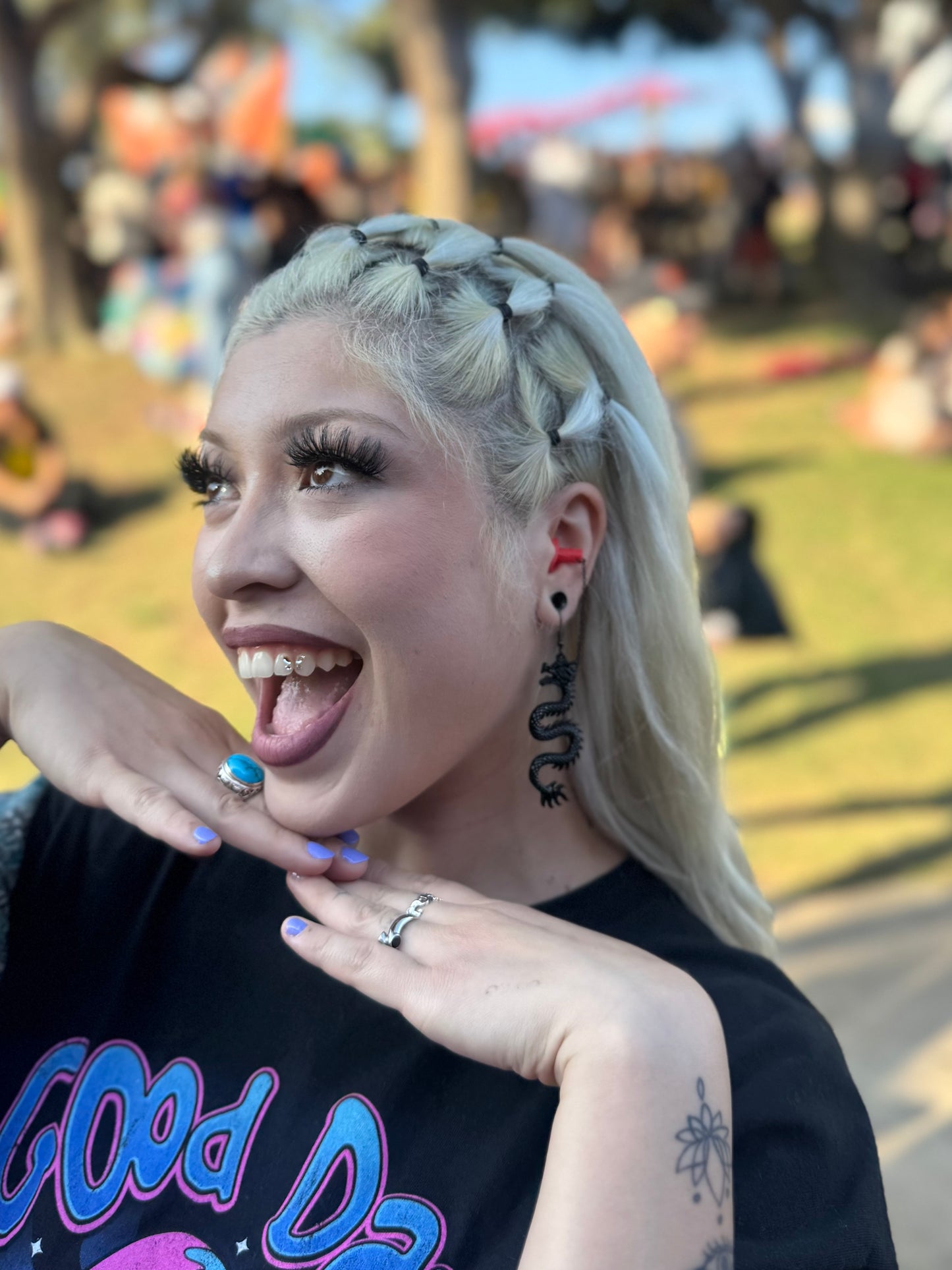 Woman wearing sensory friendly earplug earrings with black dragons and red silicone ear plugs. Zoomed in view.