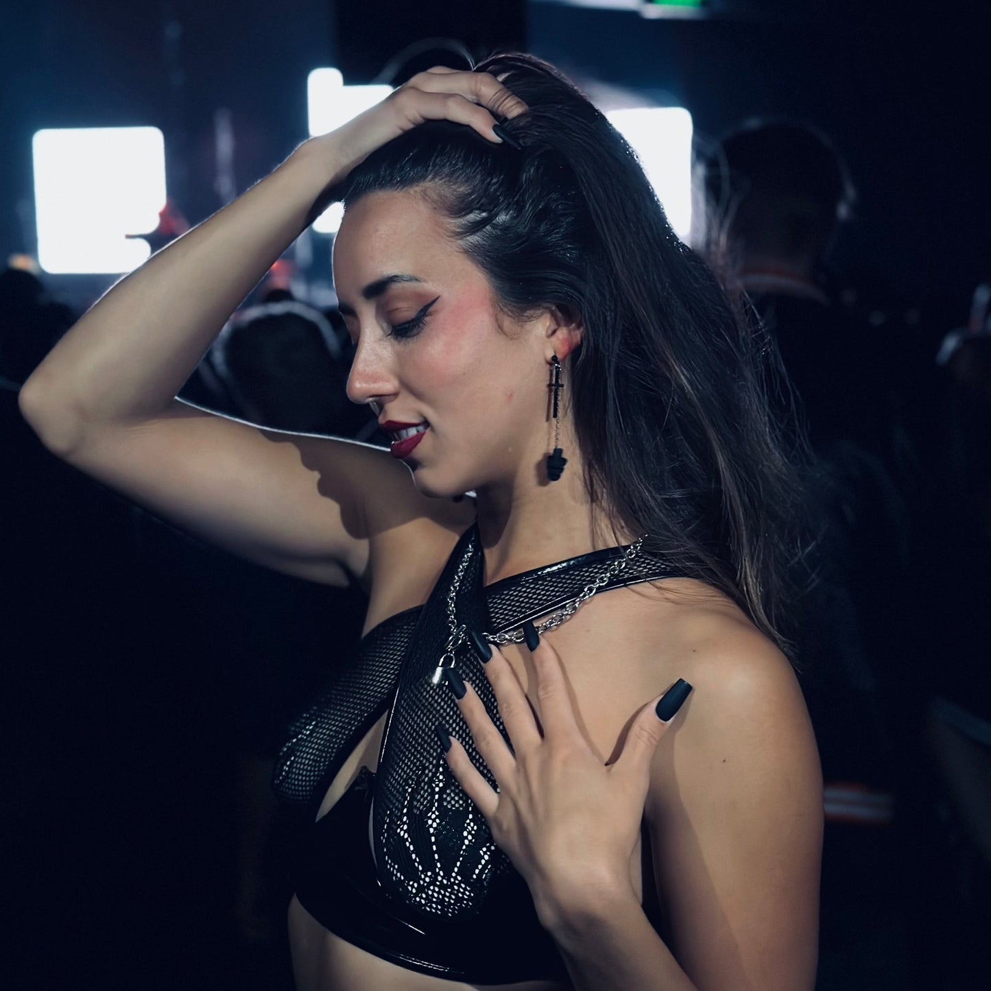 Hot woman wearing Black Sinister Earplug Earrings with black crosses and black silicone ear plugs attached. Sensory friendly jewelry for raves and concerts.