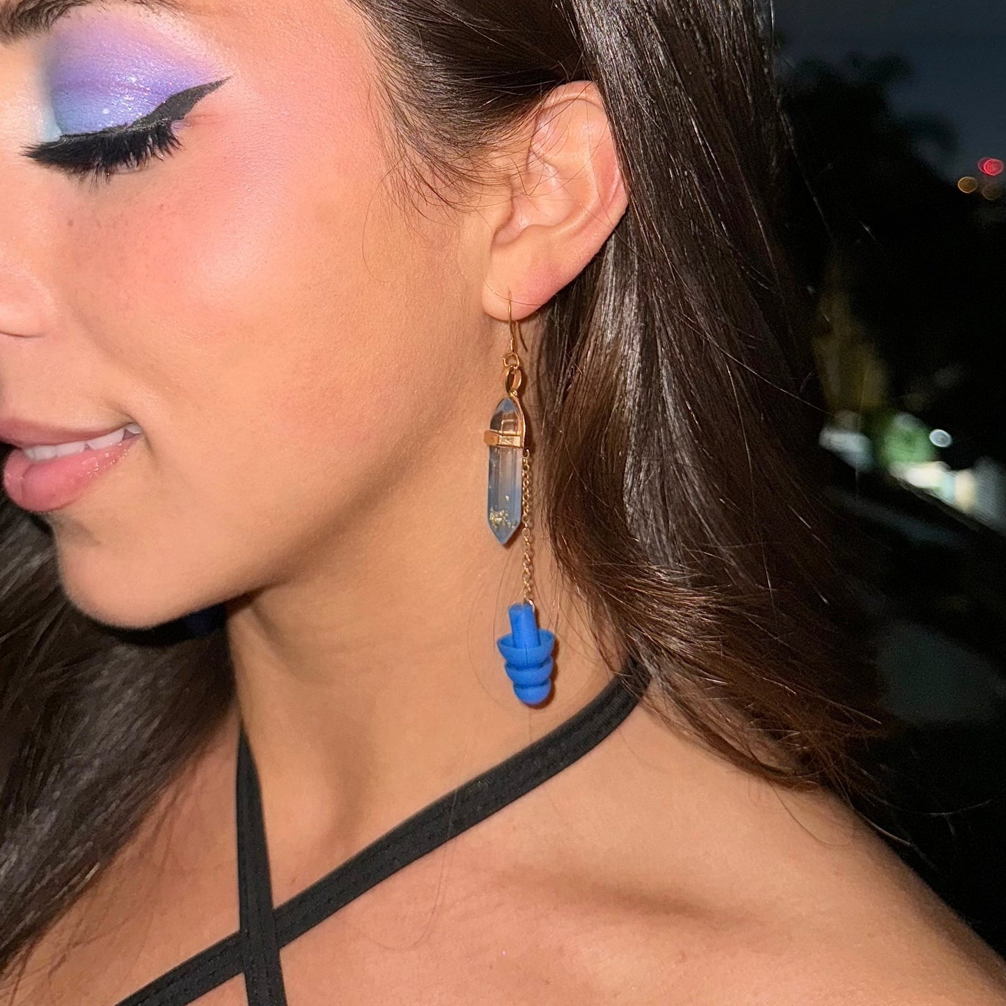 Deep blue crystal earplug earrings with a gold setting and chain. Trendy noise-reduction jewelry for ravers, festival-goers, and EDM lovers.