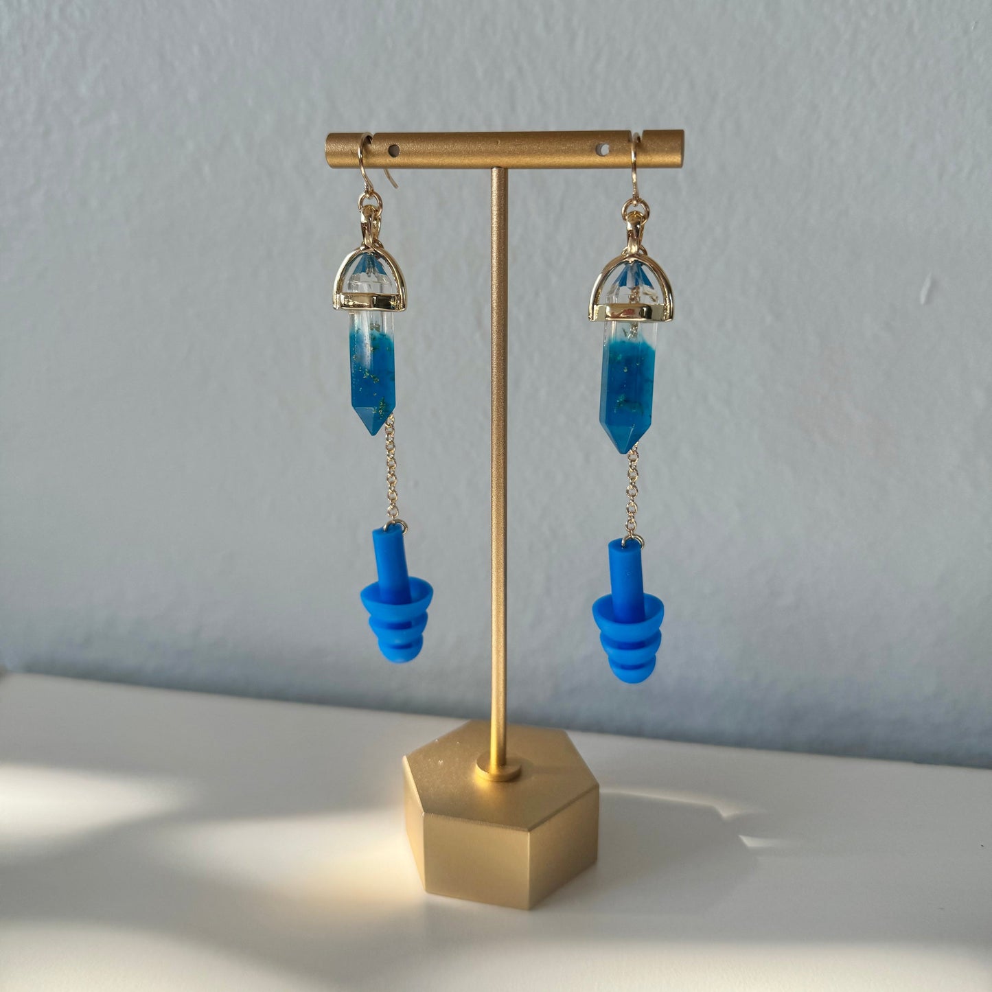 Deep blue crystal earplug earrings with a gold setting and chain. Trendy noise-reduction jewelry for ravers, festival-goers, and EDM lovers. Cute gift for ravers.
