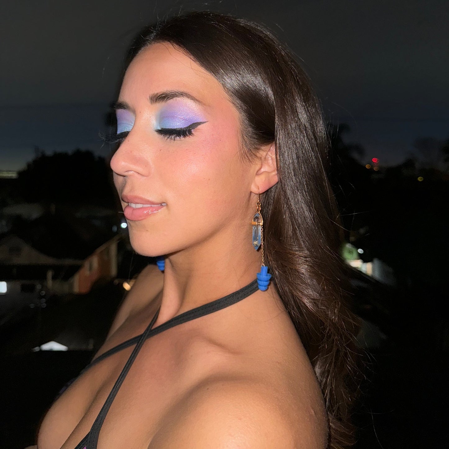 Pretty woman wearing Earplug Earrings with deep blue crystals and matching blue ear plugs with gold chain and setting. Ear plug earring jewelry offers stylish and convenient hearing protection and noise reduction. The perfect gift for ravers and edm lovers