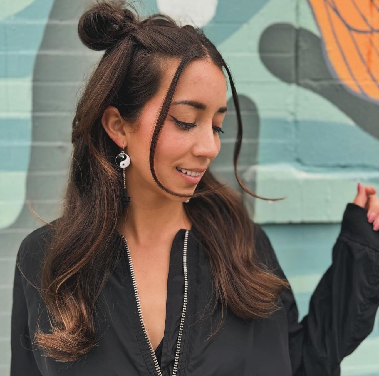 Cute girl wearing Yin and Yang earplug earrings with black and white silicone ear plugs attached. Sensory friendly jewelry for raves and concerts.