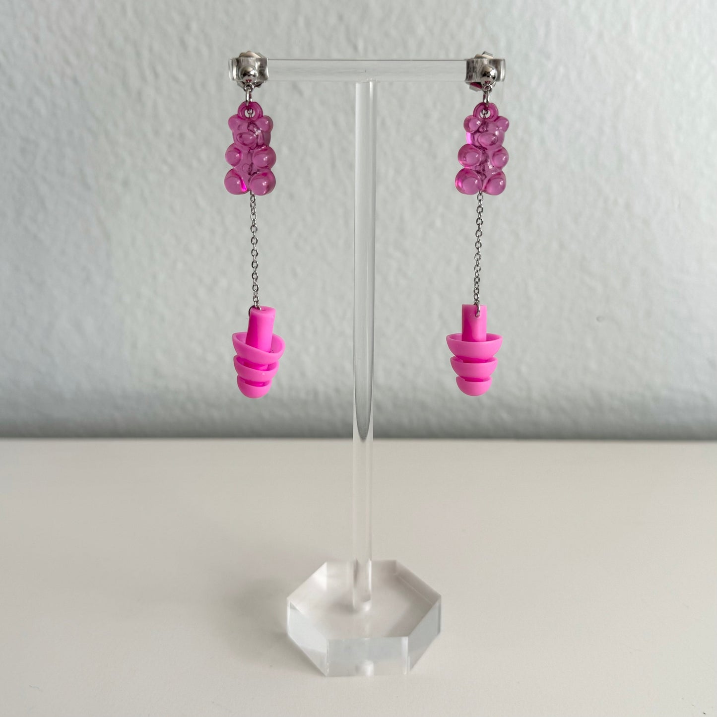 Pink gummy bear earplug earrings featuring silver chains and earplugs. A stylish and fun hearing protection gift for ravers and techno enthusiasts.