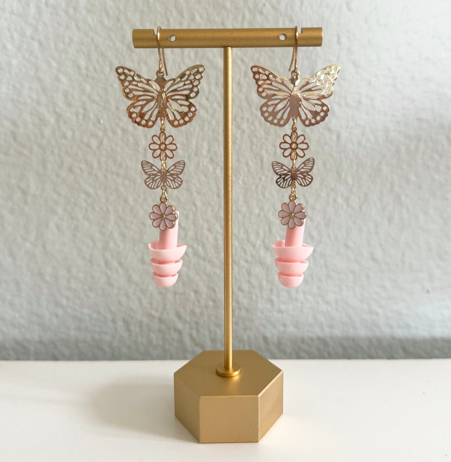 View of Pink Blossom Butterfly Earplug Earrings featuring colorful butterfly and flower designs with matching pink ear plugs. A stylish and functional accessory for hearing protection.