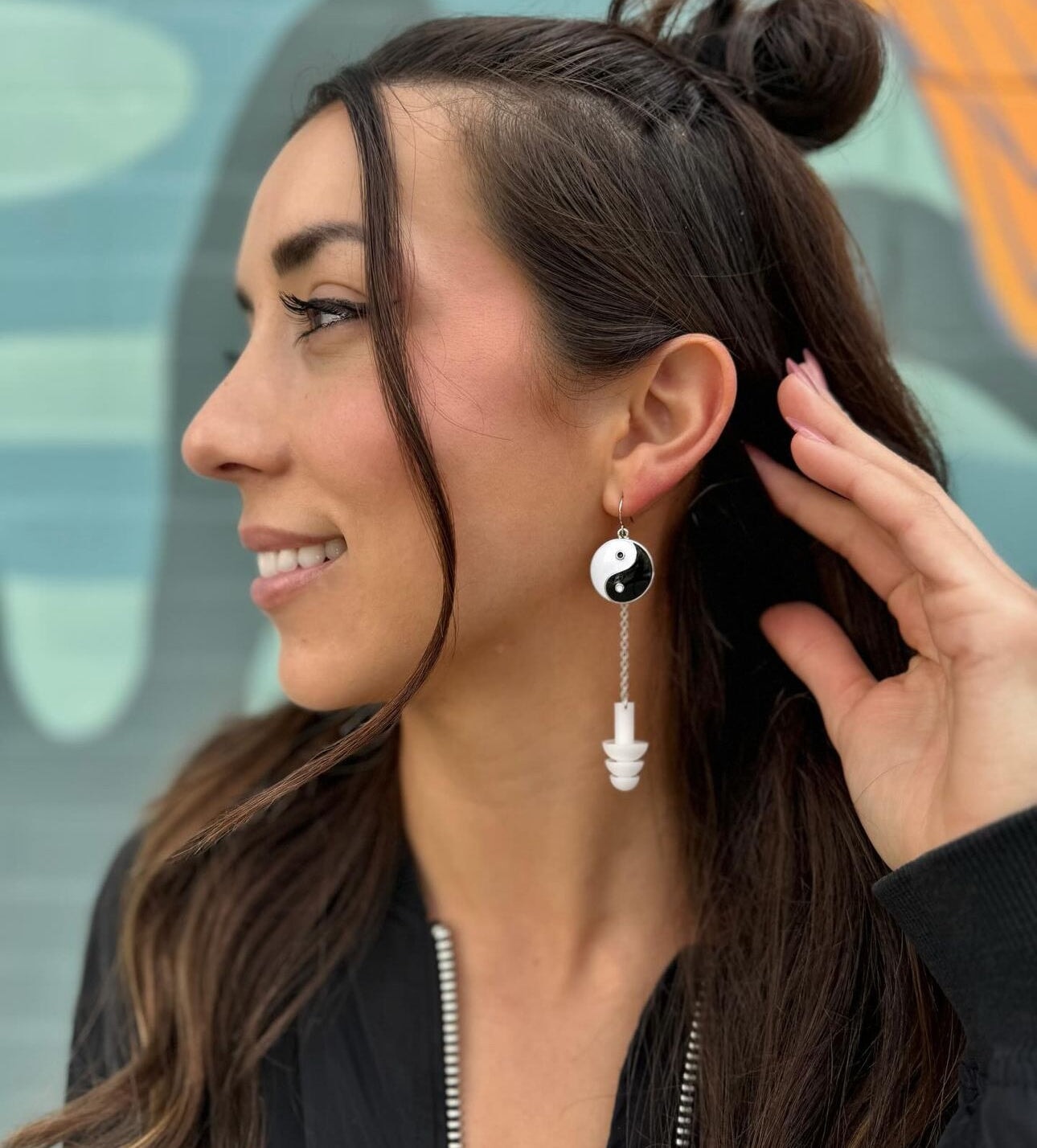 Cute girl wearing Yin and Yang earplug earrings with black and white silicone ear plugs attached. Sensory friendly jewelry for raves and concerts.