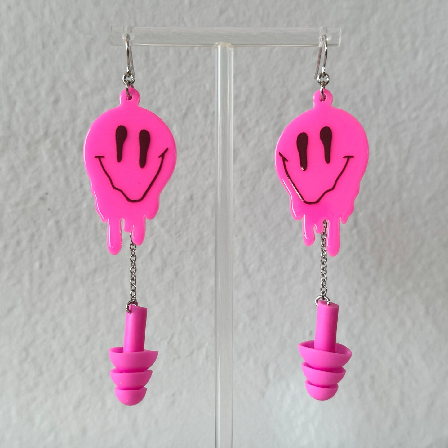 Zoomed in view of Hot Pink Melted Smiley Earplug Earrings. Perfect for ravers, these sensory-friendly earplugs provide hearing protection at events.