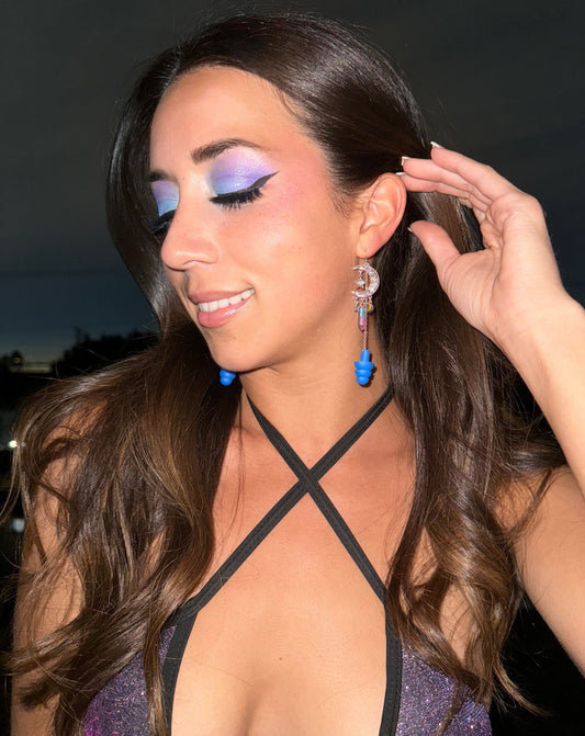 Beautiful woman in sparkling outfit wearing Midnight Moon Earplug Earrings with royal blue ear plugs attached. Stylish ear plugs for ravers.