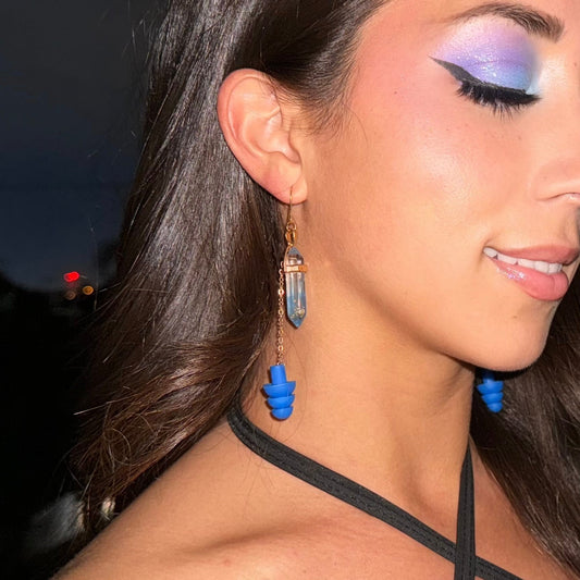 Beautiful woman wearing Stylish earplug earrings - featuring deep blue crystals, matching blue earplugs, and gold chain accents. Combines hearing protection with rave-ready fashion. Perfect gift for edm lovers.