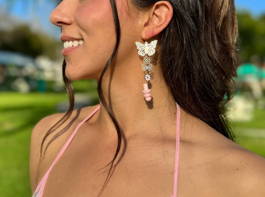View of woman wearing Pink Blossom Butterfly Earplug Earrings featuring colorful butterfly and flower designs with matching pink ear plugs. A stylish and functional accessory for hearing protection.