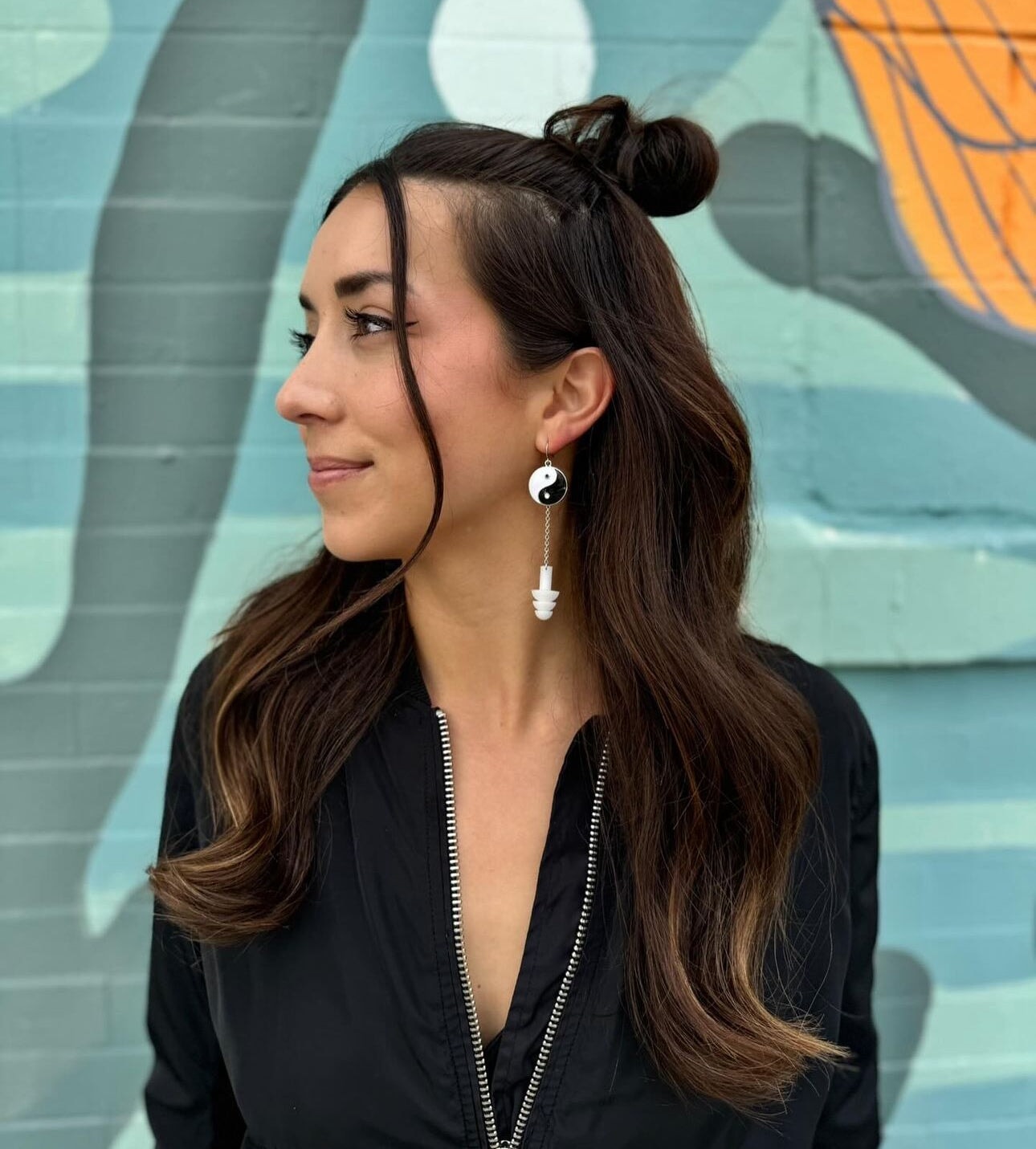 Cute girl wearing Yin and Yang earplug earrings with black and white silicone ear plugs attached. Sensory friendly jewelry for raves and concerts.