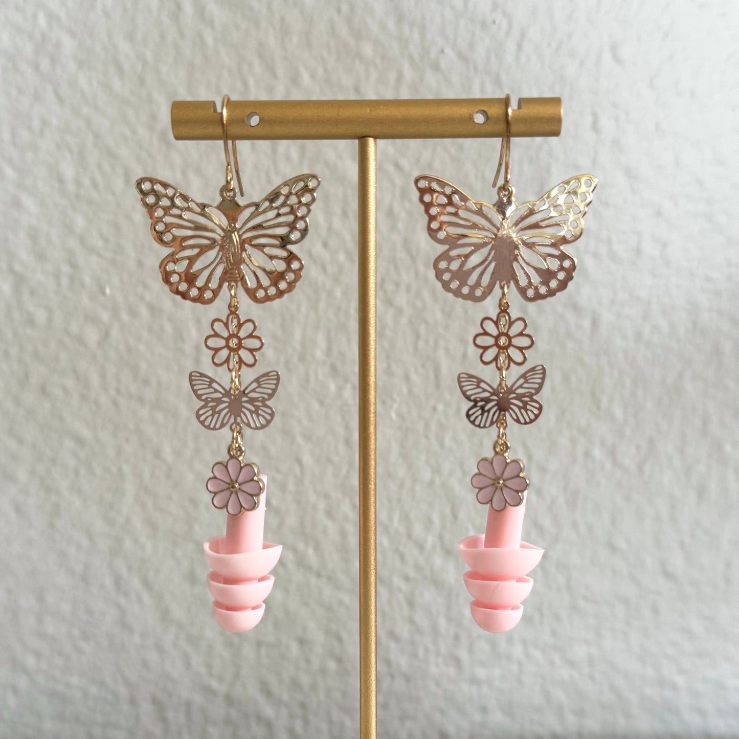 Zoomed in view of Pink Blossom Butterfly Earplug Earrings featuring colorful butterfly and flower designs with matching pink ear plugs. A stylish and functional accessory for hearing protection. Rave Day accessory.