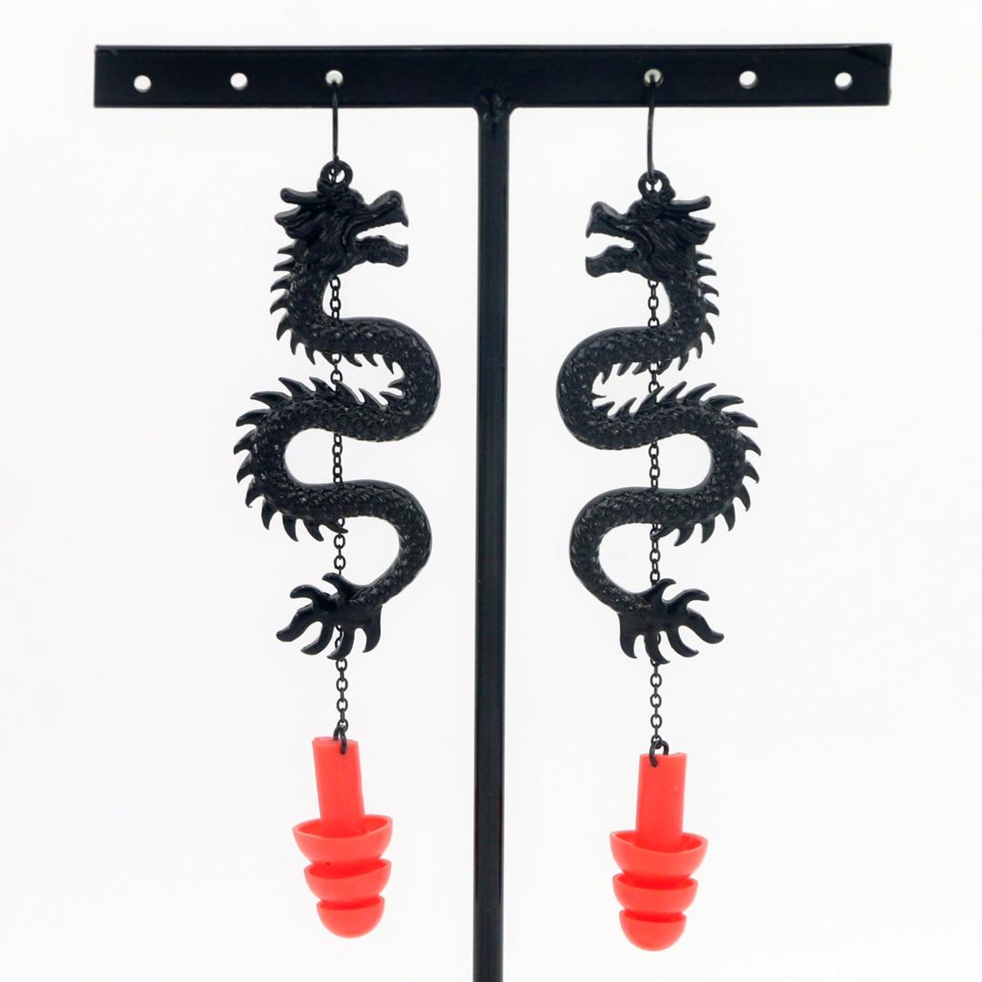 Black Dragon ear plug earrings with red silicone ear plugs attached. Hanging from earring stand.