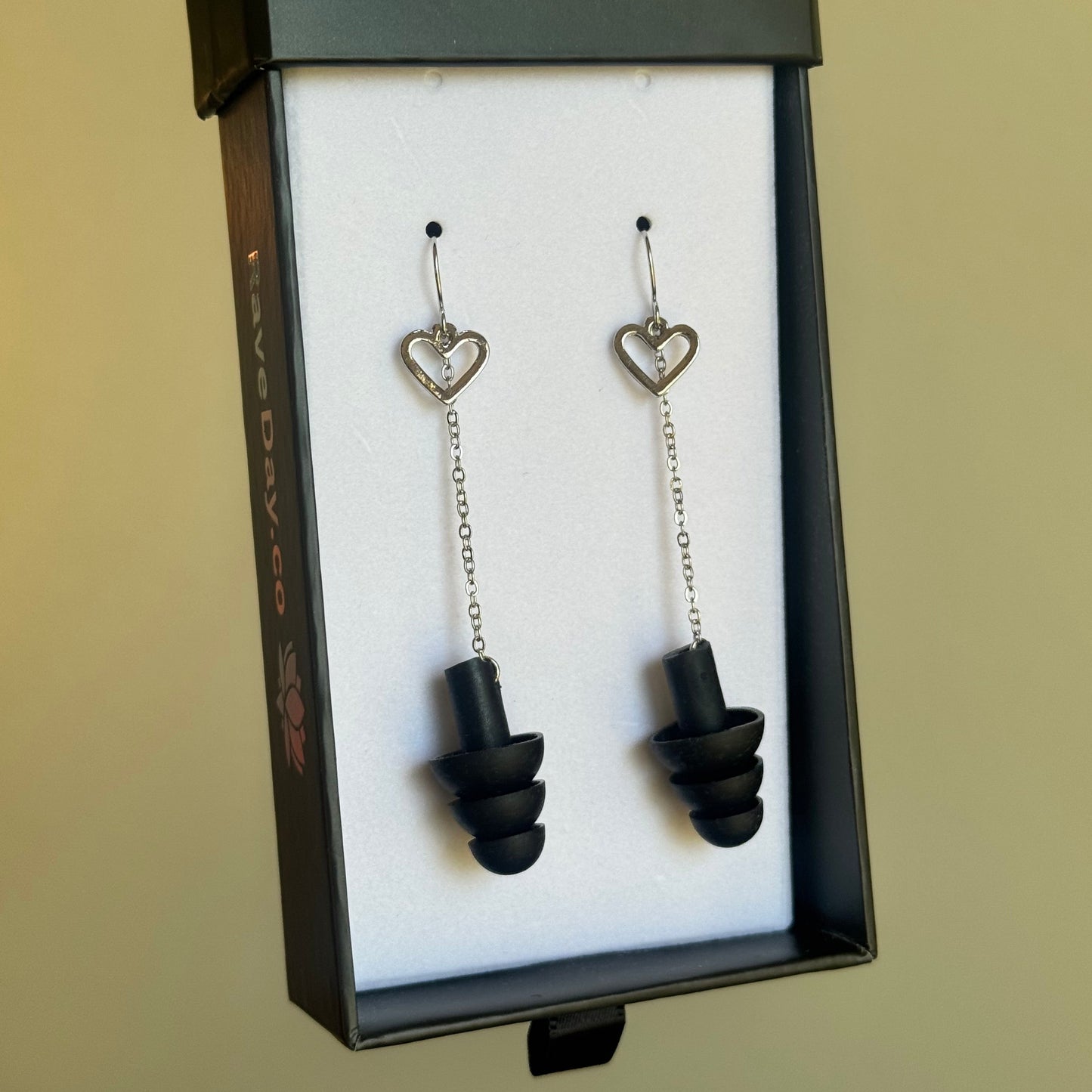 Pair of black earplugs in a display box on a beige background