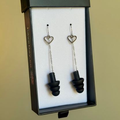 Pair of black earplugs in a display box on a beige background