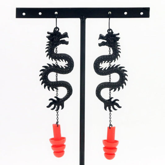 Black Dragon ear plug earrings with red silicone ear plugs attached.  Hanging from earring stand. 